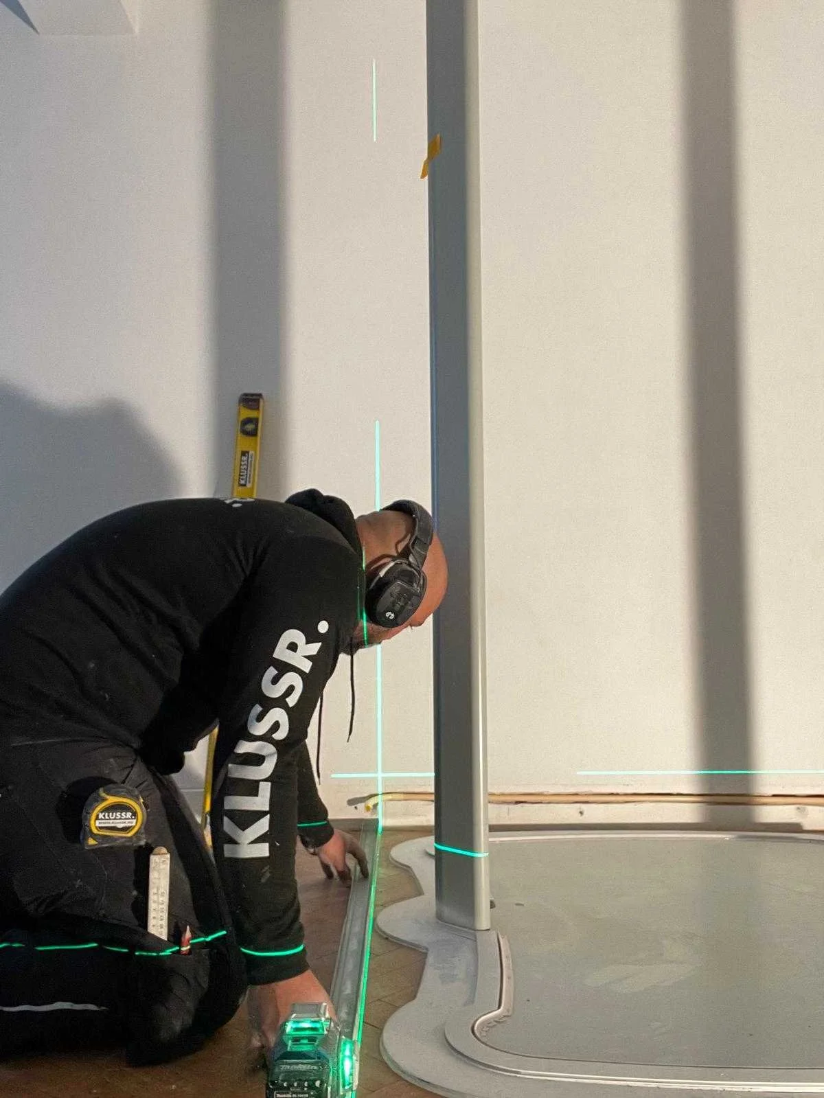 Vakman van KLUSSR. meet een wand uit met een laser